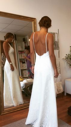 a woman standing in front of a mirror wearing a white dress