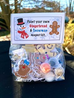 gingerbread and snowman magnet kit in a plastic bag on a black table outside