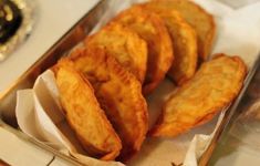 some fried food is sitting in a metal container on a table next to silverware