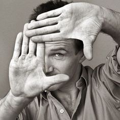 a black and white photo of a man holding his hands up to his face with both hands