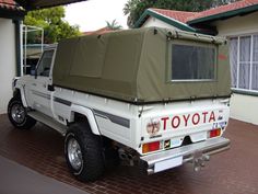 a white truck parked in front of a house with a tent on the back of it