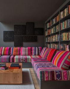 a living room filled with furniture and bookshelves covered in colorful striped blankets on top of each other