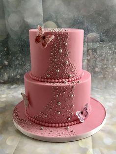 a three tiered pink cake with butterflies on it