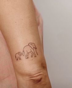 an elephant and calf tattoo on the left arm by someone's leg with one hand