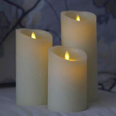 three lit candles sitting on top of a bed