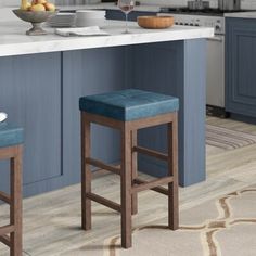 two blue stools in front of a kitchen island with white counter tops and gray cabinets