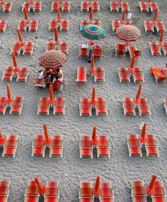 many chairs and umbrellas are set up on the beach for people to sit in