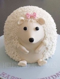 a white cake with a hedge on it's side and a pink bow on its head