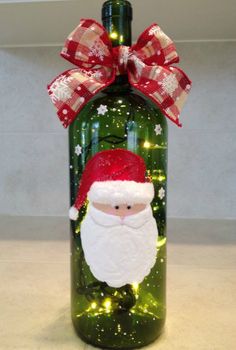 a green bottle with a santa clause on it and lights around the top, as well as a red bow