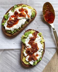 two pieces of bread with various toppings on them next to a spoon and knife