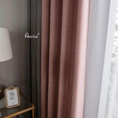 the curtains in this room are pink and grey, with a white lamp next to them