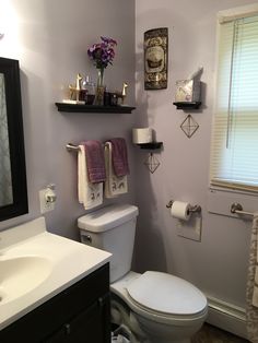 a white toilet sitting in a bathroom next to a sink under a mirror and towel rack