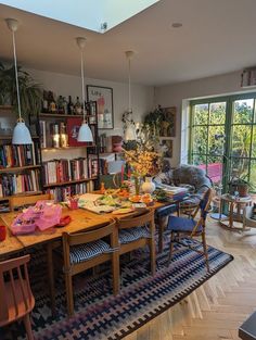 a dining room table and chairs in front of a large book shelf filled with books