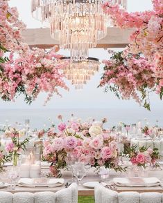 an outdoor dining area with pink flowers and chandelier