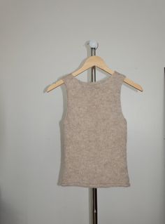 a white tank top hanging on a wooden hanger