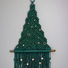 a green crocheted christmas tree hanging from a wooden rack with beads and stars