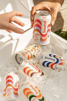 a person holding a can of soda in an ice chest with other cans around it