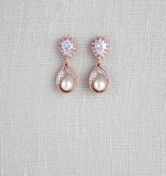 two pairs of pearl and diamond earrings on top of a white fabric background with the word love