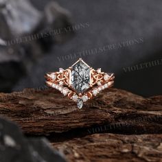 a diamond ring sitting on top of a piece of wood in front of some rocks