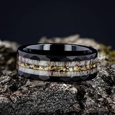 a black and white ring with gold inlays sitting on top of a rock