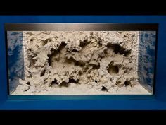 an aquarium filled with rocks and water inside of it's glass case on a blue background