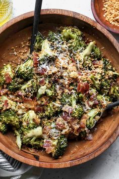 a wooden bowl filled with broccoli covered in cheese and other toppings on top of a table