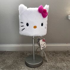 a hello kitty lamp with a pink bow on it's head sitting on the floor