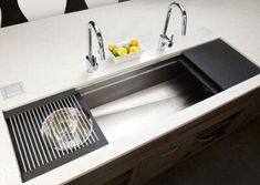 a kitchen sink with two faucets and a bowl of fruit on the counter