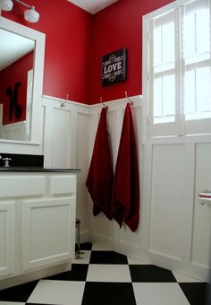 a black and white checkered floor in a bathroom with red towels hanging on the wall