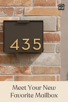 a black mailbox with the number 435 on it is next to a brick wall