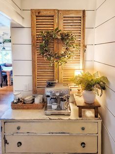 an old dresser with a coffee maker on it and some plants in the window sill