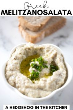 a white bowl filled with hummus next to two slices of bread