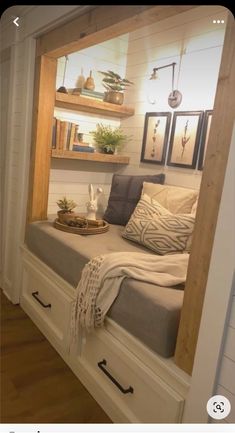 a bed sitting under a window next to a shelf filled with books and other items