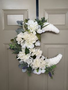 a wreath with white flowers and greenery hangs on the front door to welcome guests