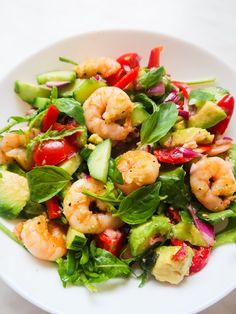 a salad with shrimp, avocado, and red peppers on a white plate