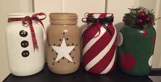 four decorated mason jars sitting on top of a table next to each other with christmas decorations in them