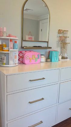 a white dresser topped with lots of drawers and a pink purse on top of it