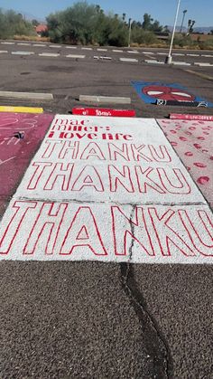 a parking lot with chalk writing on the ground in front of an empty parking lot