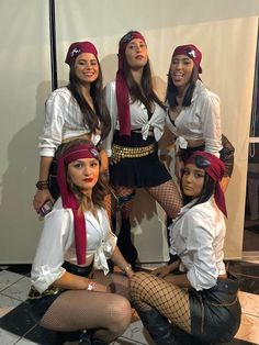 four women dressed up in pirate costumes posing for a photo together with one woman sitting on the floor