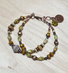 "Rustic and earthy double strand boho bracelet, great for everyday. This was created using a Czech glass bicone bead in cream and etched with a brown wash as a focal, Czech Picasso glass beads in sage, camel, cream, and a dark mustard.  I have also used antique copper accent beads throughout.  The extender chain is finished with a green Czech glass flower bead, and a copper dragonfly charm.    Bracelet best fits a wrist size between 6-3/4\" - 7-1/2\".  If a longer extender is needed, please leav Bohemian Multi-strand Hand-strung Bracelets, Bohemian Multi-strand Bracelets, Bohemian Multi-strand Adjustable Bracelets, Adjustable Multi-strand Festival Bracelets, Earthy Hand Wrapped Bracelets For Festival, Earthy Hand Wrapped Bracelet For Festivals, Bohemian Adjustable Copper Bracelets, Adjustable Brown Bracelet With Lobster Clasp, Adjustable Brown Bracelets With Lobster Clasp