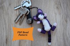 a crocheted keychain with a stuffed animal on it sitting next to a pair of keys