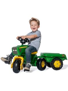 a young boy riding on the back of a green tractor with yellow wheels and tires