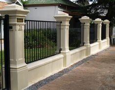 an iron fence and gate in front of a white house with black wrought iron fencing