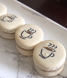 three macaroons with writing on them sitting on a white plate next to another macaroon