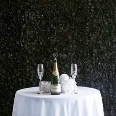 a table with two champagne glasses and an empty bottle sitting on it next to some ice cubes