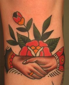 a close up of a person's arm with flowers on it and two hands holding each other