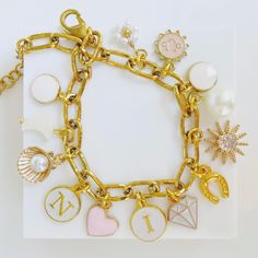 a close up of a bracelet on a white surface with charms and other items attached to it