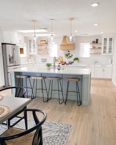 a kitchen with white cabinets and blue counter tops, an island in between two chairs