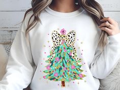 a woman wearing a white sweatshirt with a christmas tree on the front and leopard print on the back