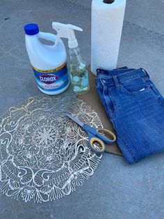 a pair of blue jeans sitting on top of a floor next to a bottle of cleaner